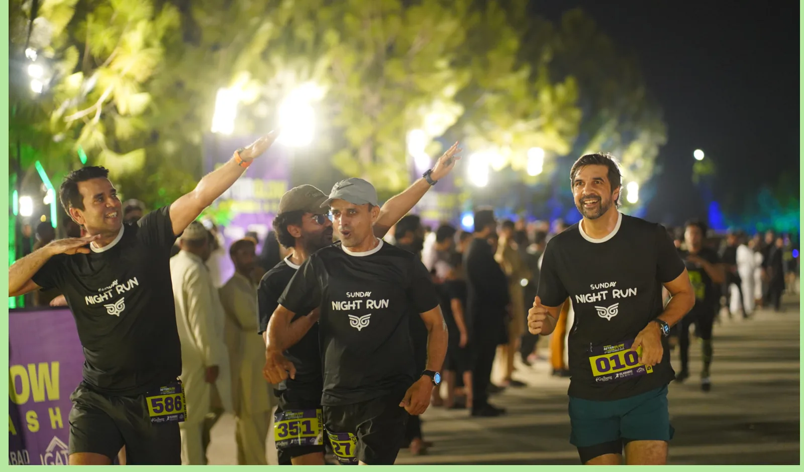 Finishers in event shirts walking through the crowd with their arms raised