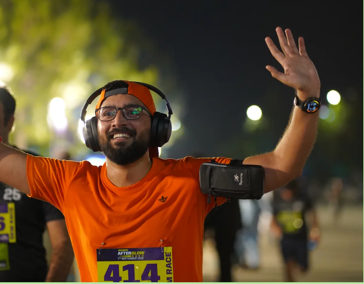 A runner in bib 414 with both arms raised approaching the finish
