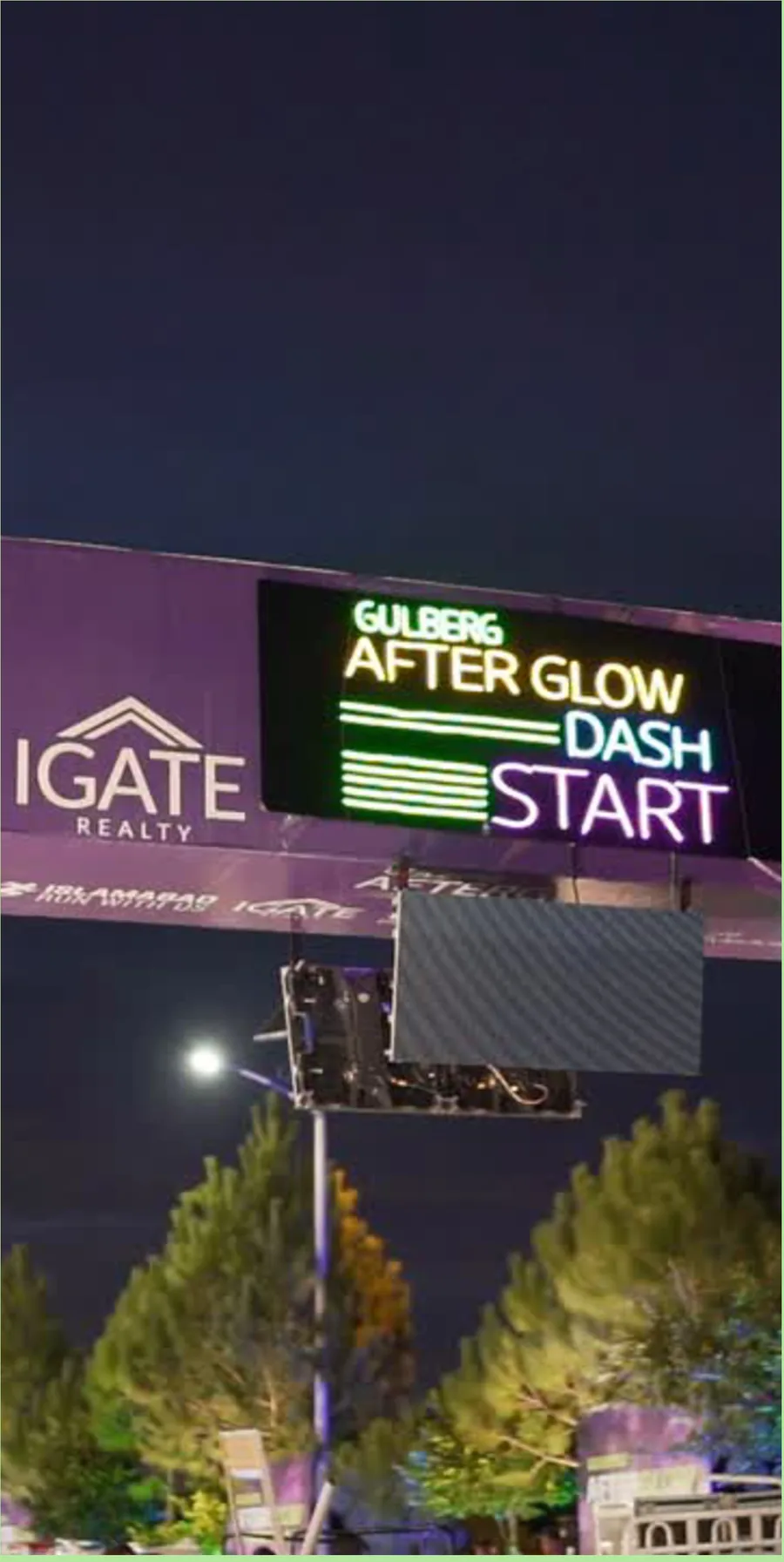 The illuminated AfterGlow Dash start gantry at night above the IGATE Realty banner
