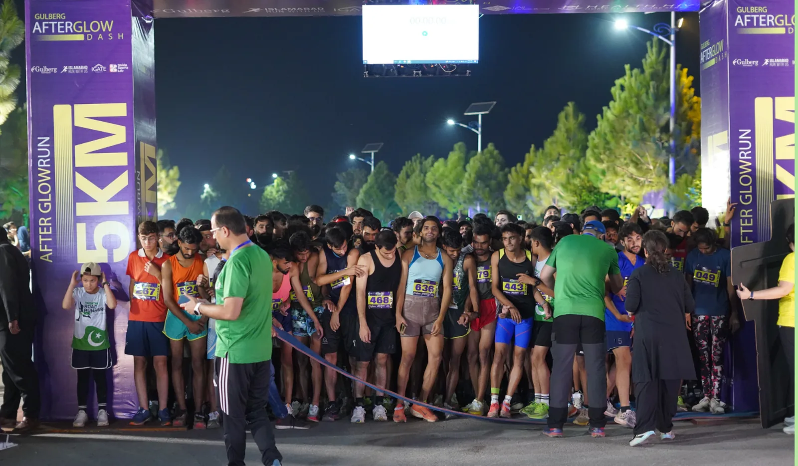 Runners packed behind the 5km start line between branded gantry towers