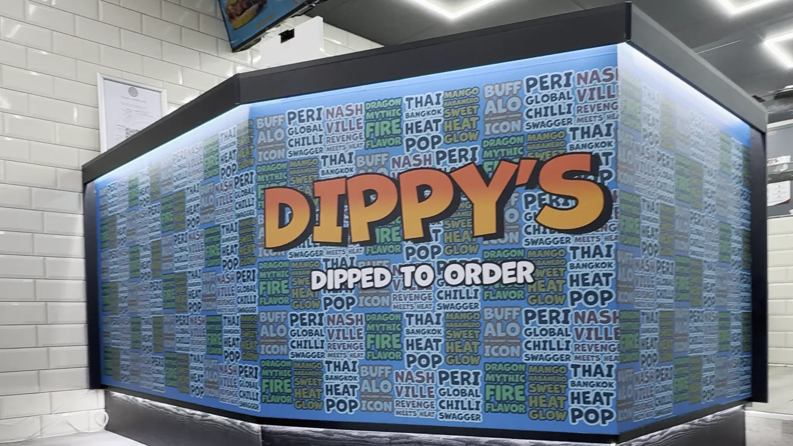 The counter, wrapped in a repeating flavour-name pattern with the wordmark centred, under the digital menu boards