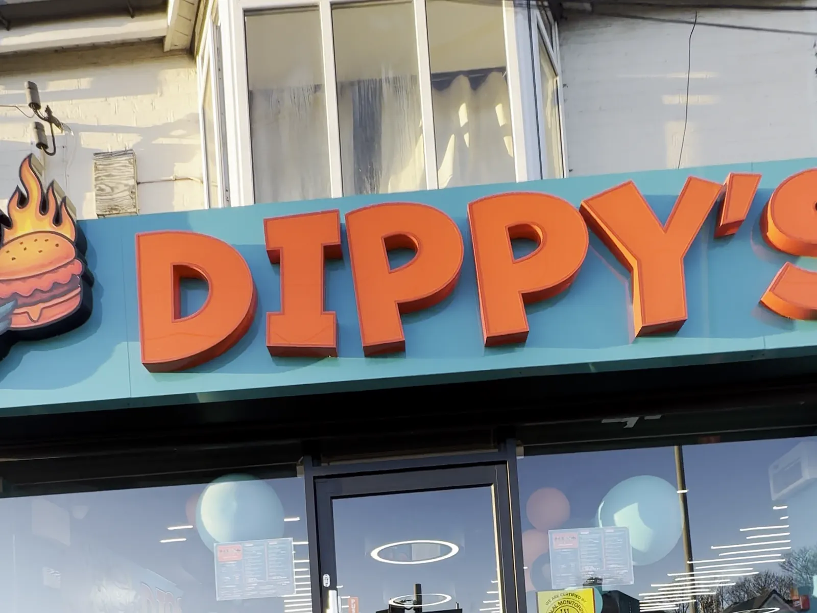 The Dippy's shopfront: raised orange letters on a teal fascia above glass doors